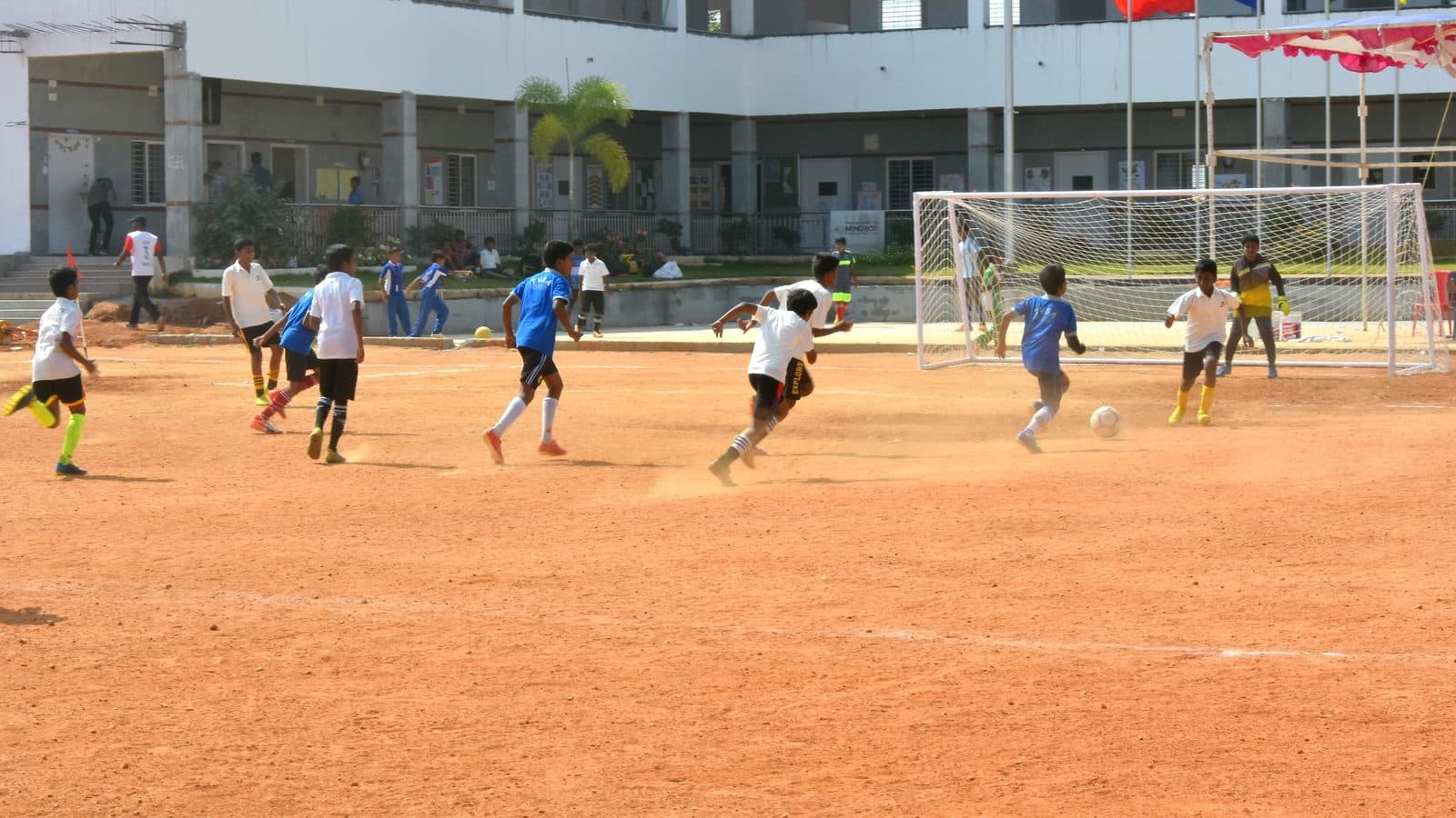 Schoolboys contest a football on a red-dirt pitch during a youth tournament in Hosur and Bengaluru