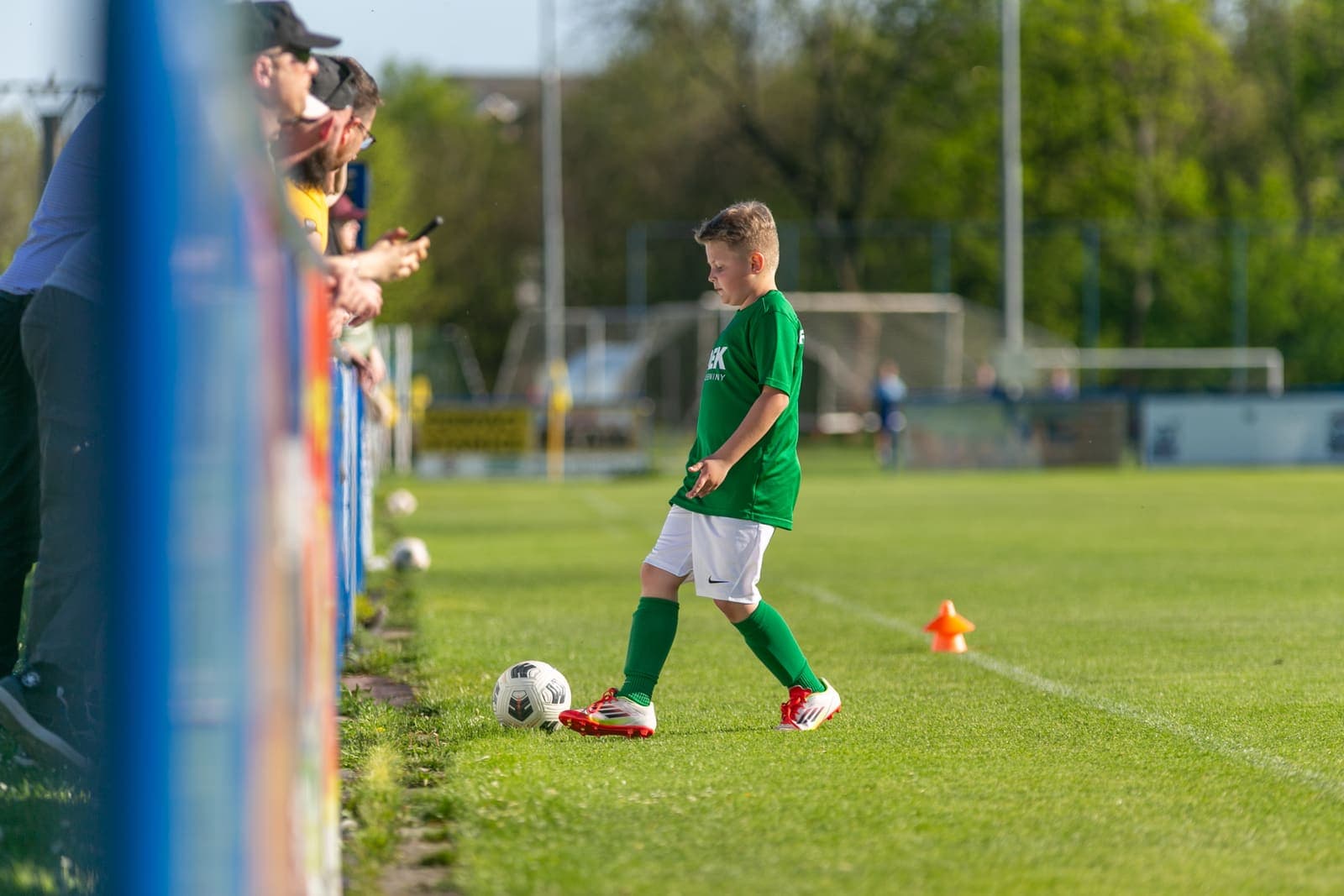 Young footballer walking the ball along the touchline during training