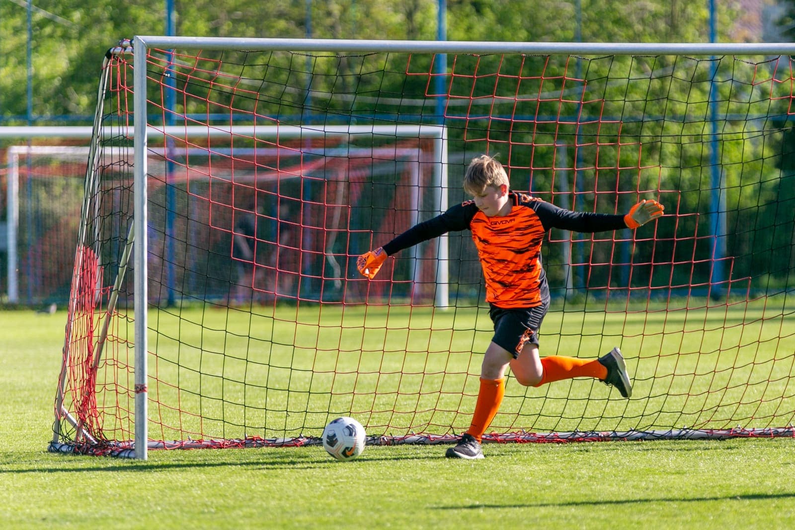 Young goalkeeper kicking a football clear of the goal