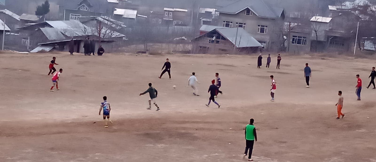 Two teams playing football at Midoora sports ground, India — ball in play