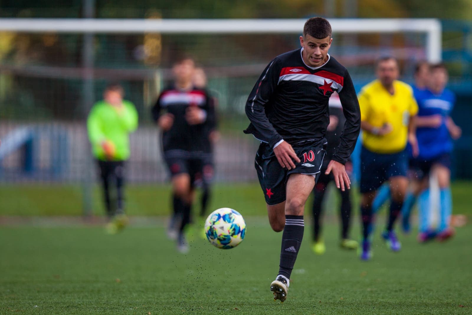 Youth footballer running onto a bouncing ball during a match