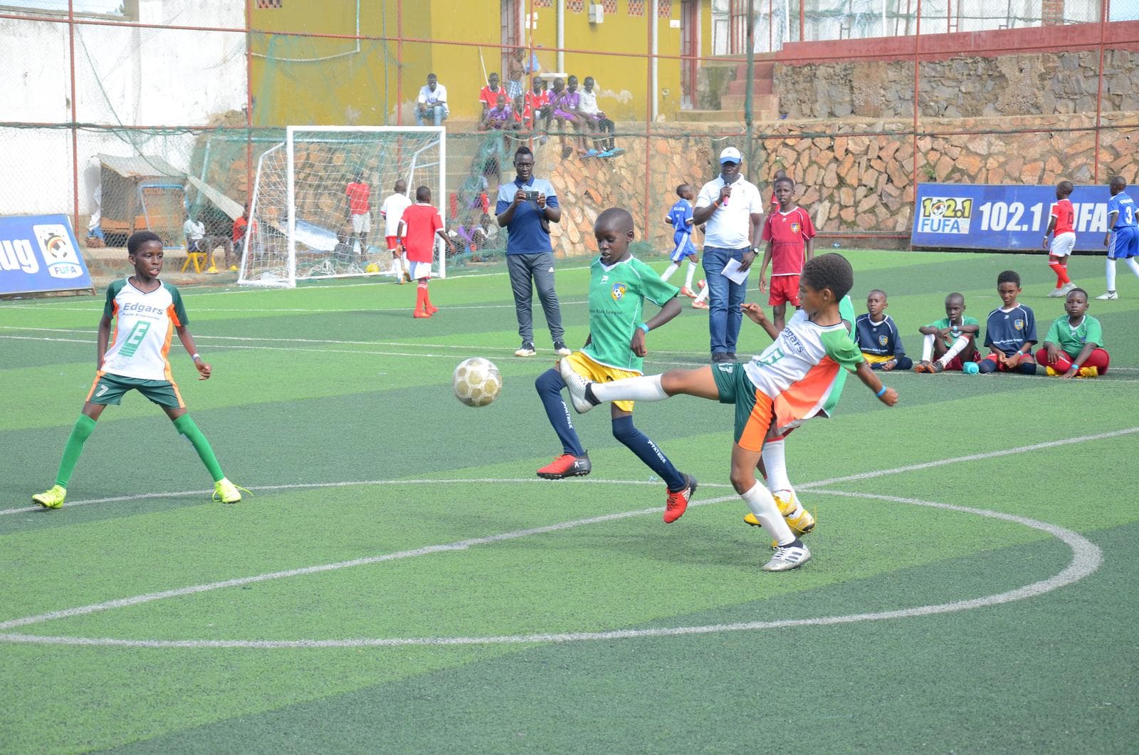 Youth footballers contest a ball during a Uganda Youth Football Association league match