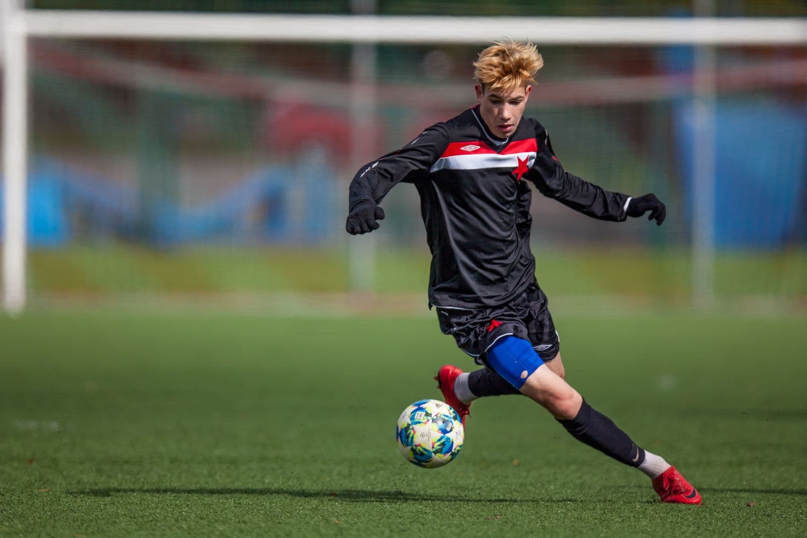 Youth footballer striking a football on an artificial pitch