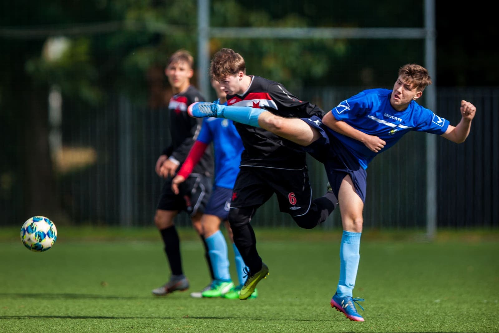 Youth footballers contesting a bouncing ball during a match