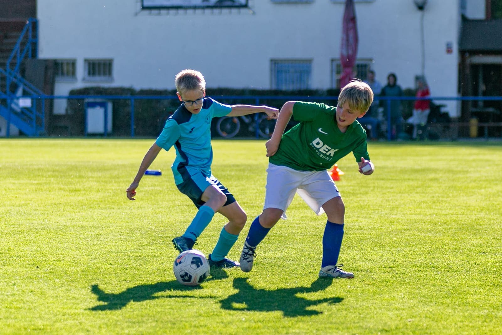 Two young footballers contesting the ball on a grass pitch