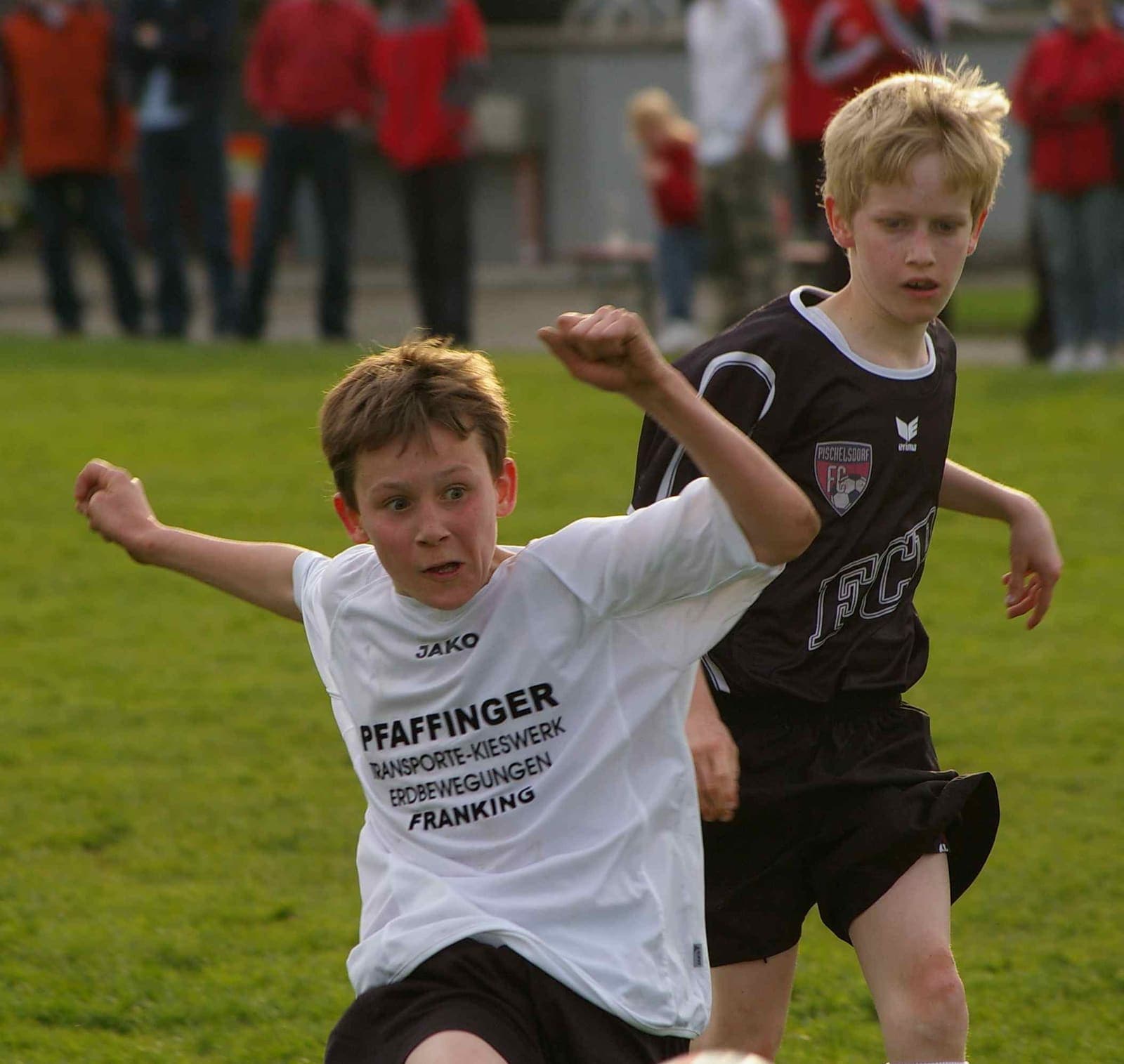 Young footballer striking the ball as an opponent closes in