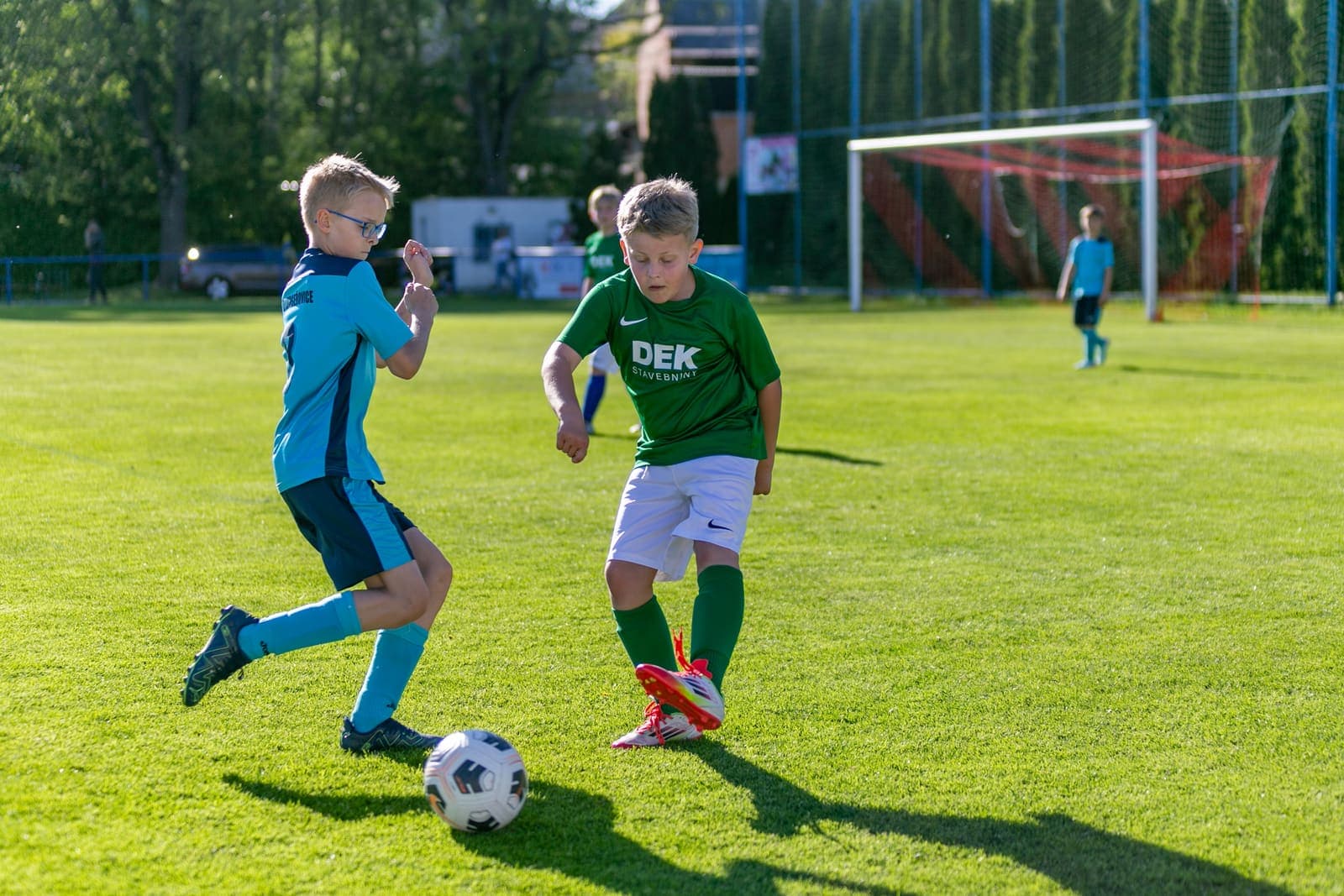 Two young footballers contesting the ball on a grass pitch