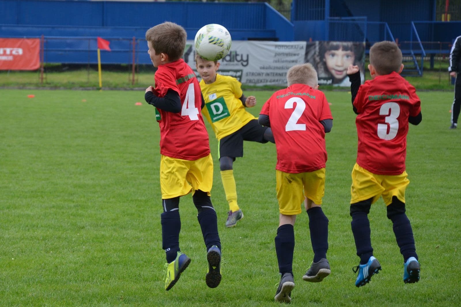 Young children jumping to head a football