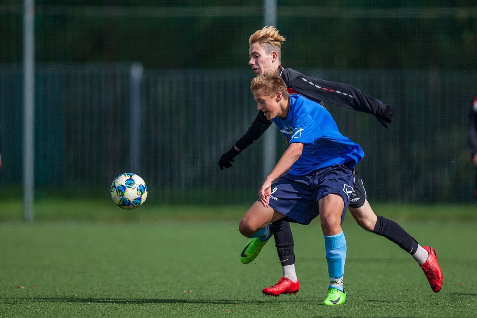 Two youth footballers competing for an airborne ball