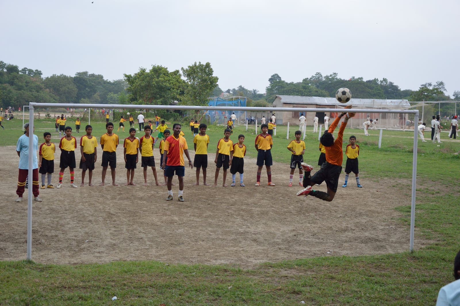 Goalkeeper leaping for a football during youth training on an Indian ground in Howrah