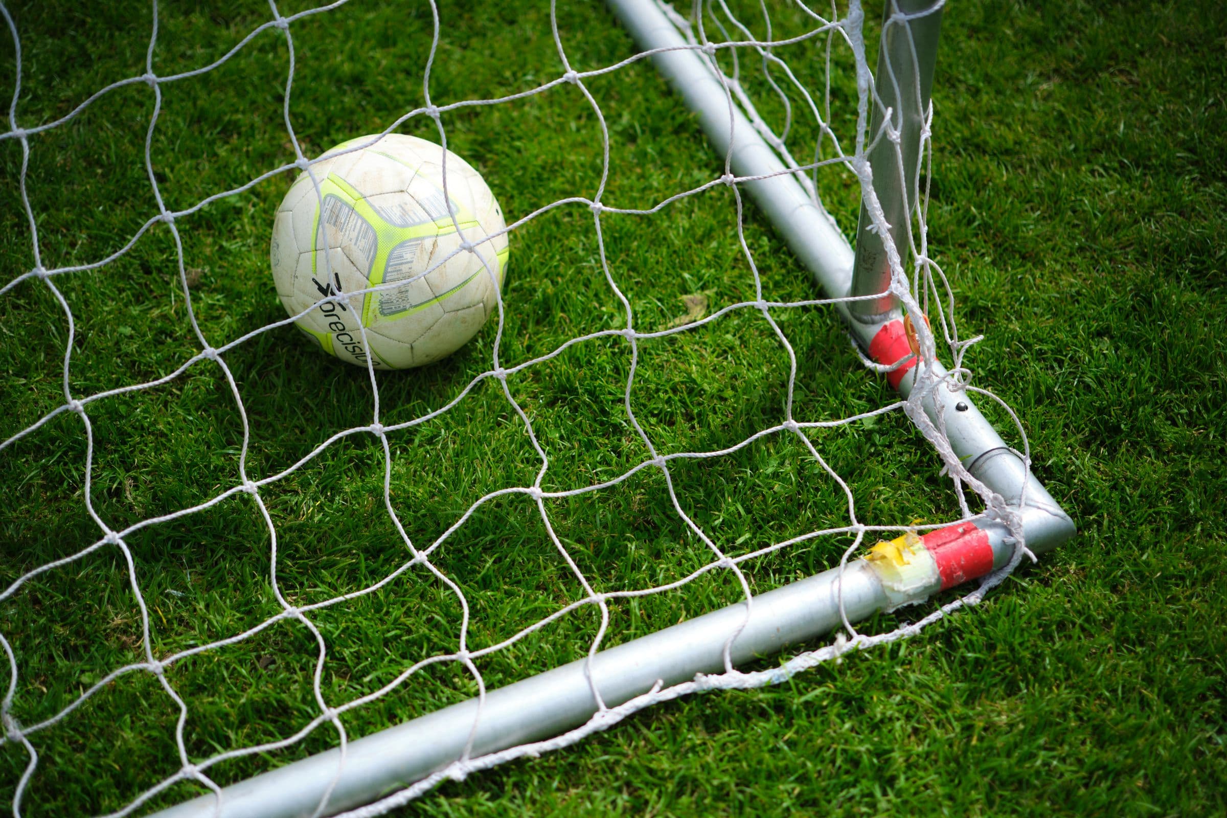 Soccer ball in goal net on grass