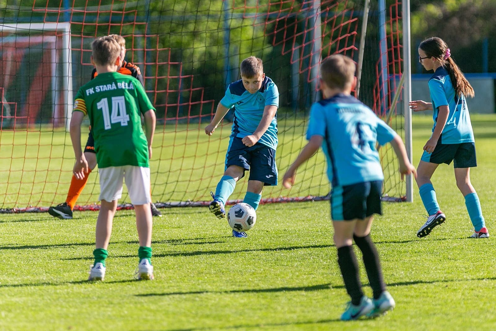 Youth footballers contesting the ball in front of goal
