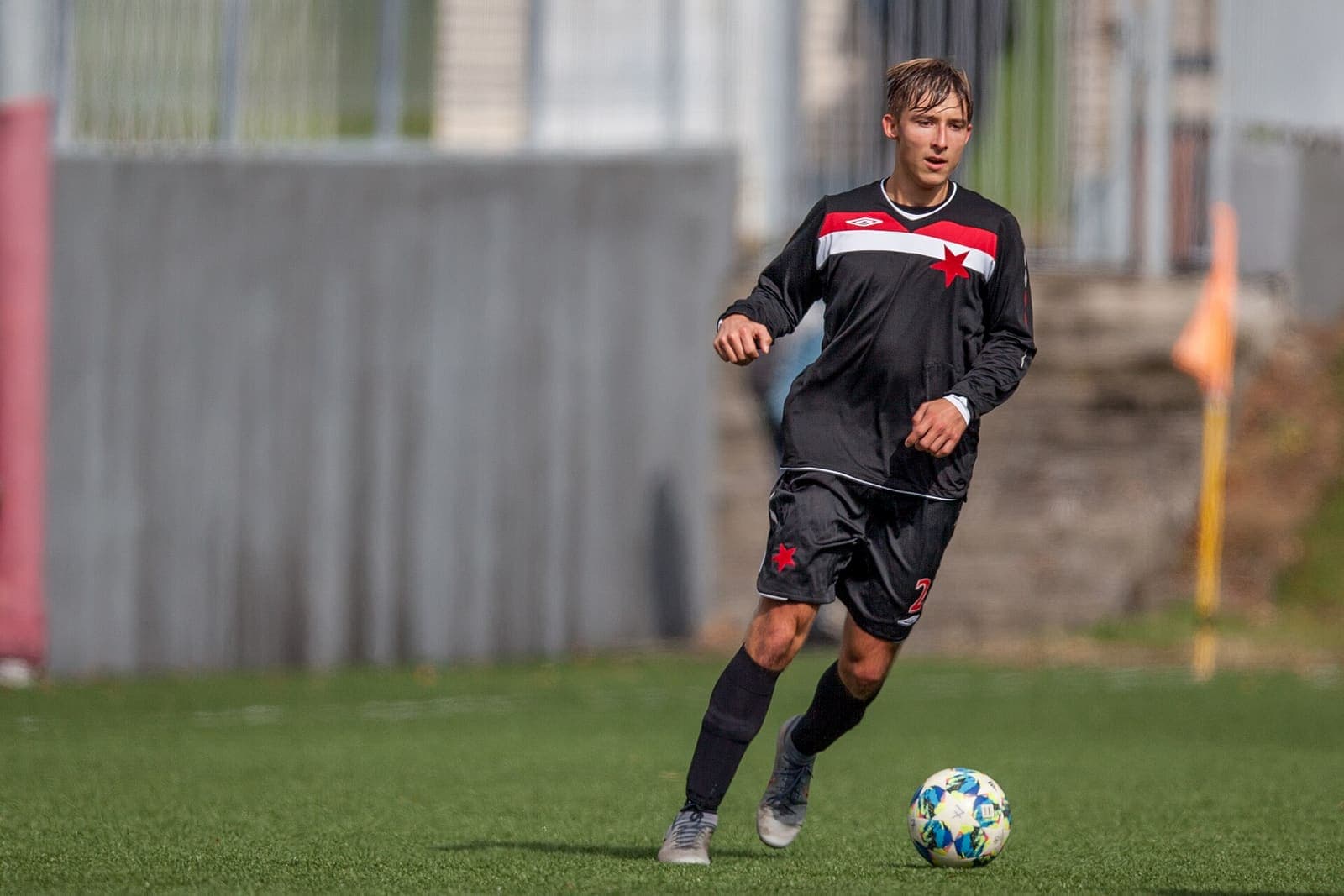 Youth footballer dribbling the ball on a grass pitch