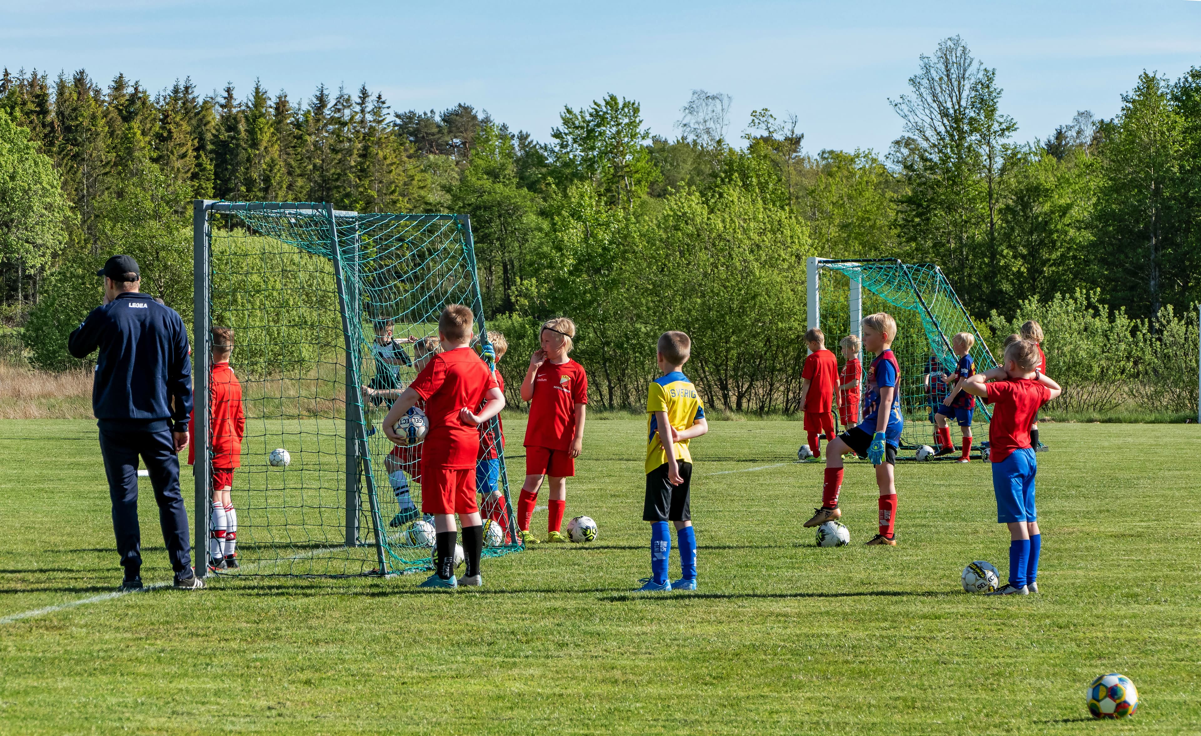 Kids practising football dribbling on training pitch.
