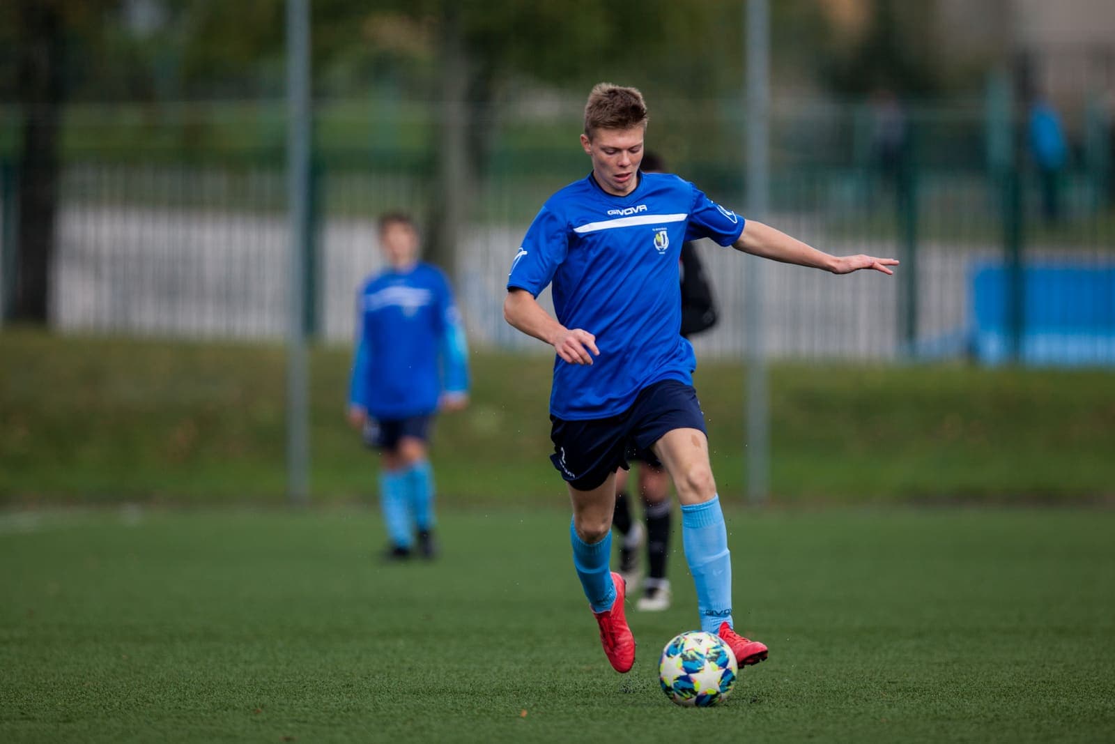 Youth footballer dribbling the ball on a grass pitch