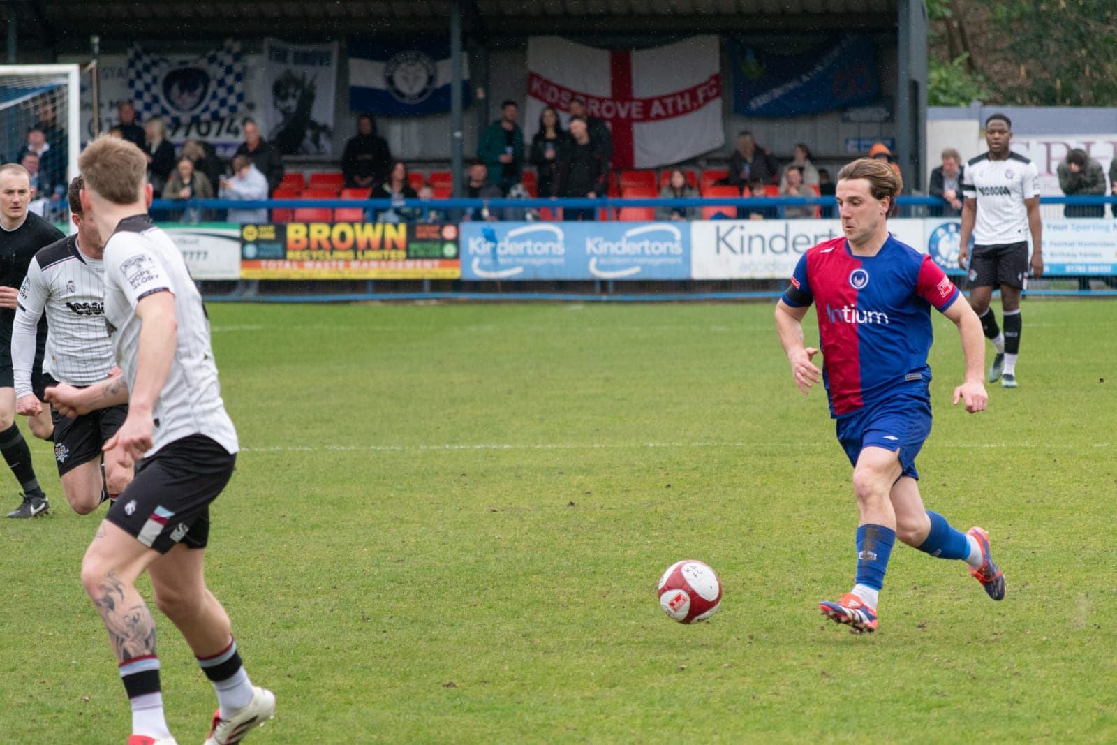 Non‑league football match action with players challenging for the ball