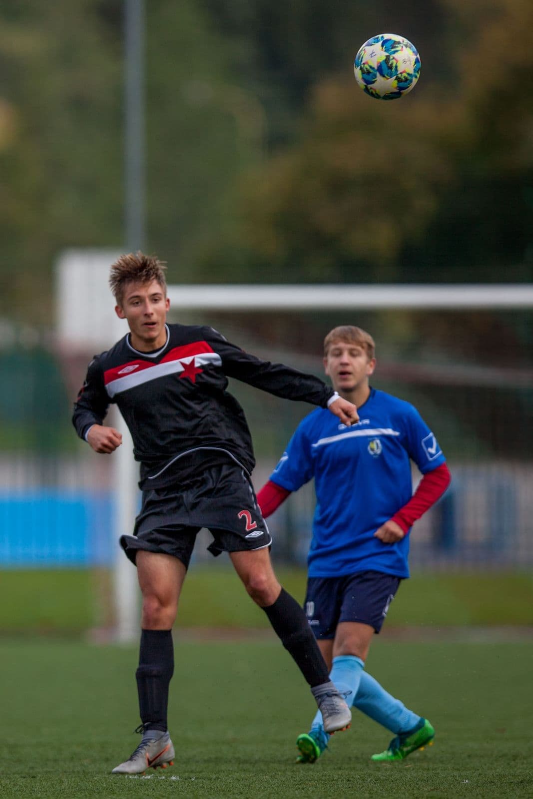 Youth footballer tracking a high ball with a teammate nearby