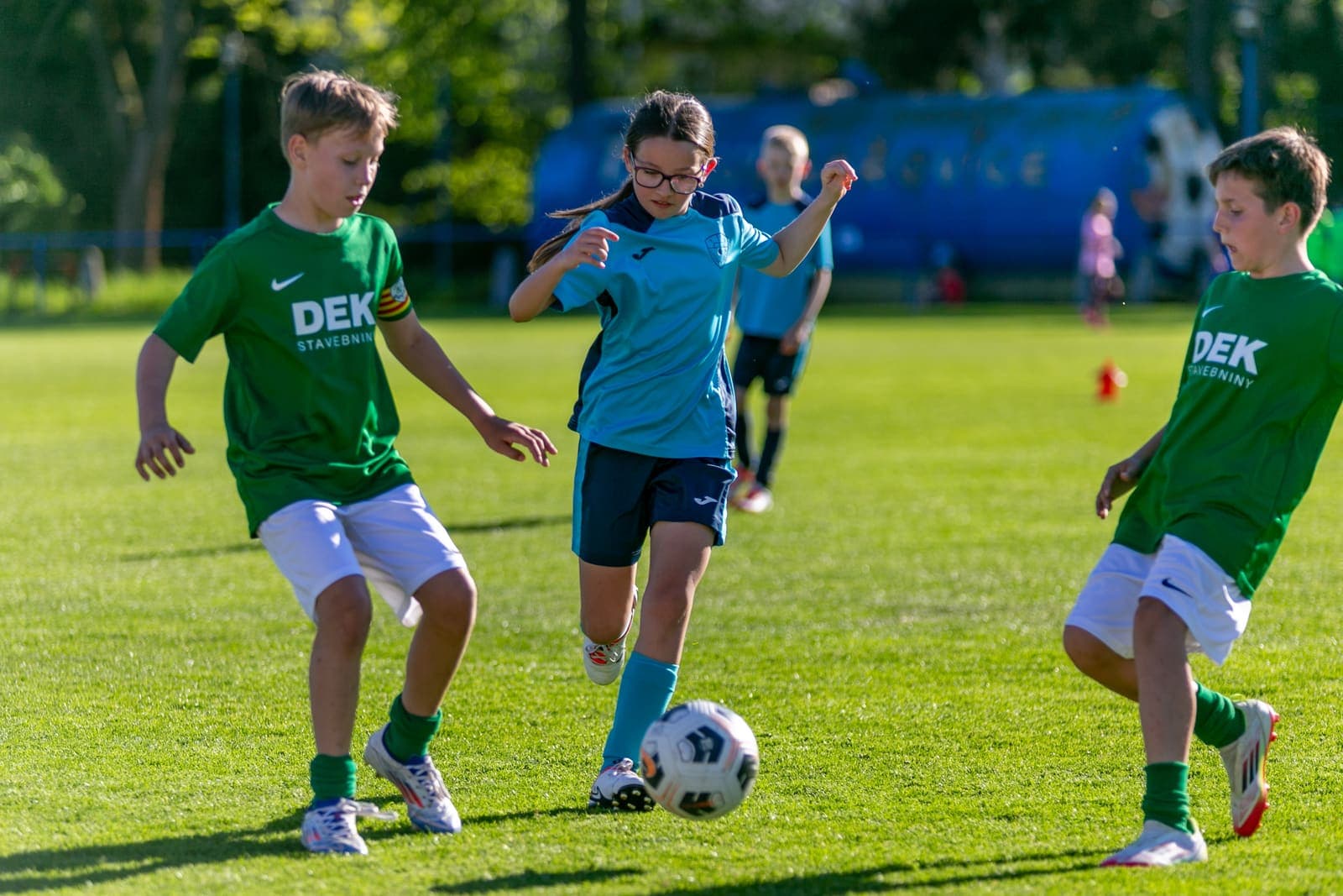 Three young footballers contesting the ball during a match