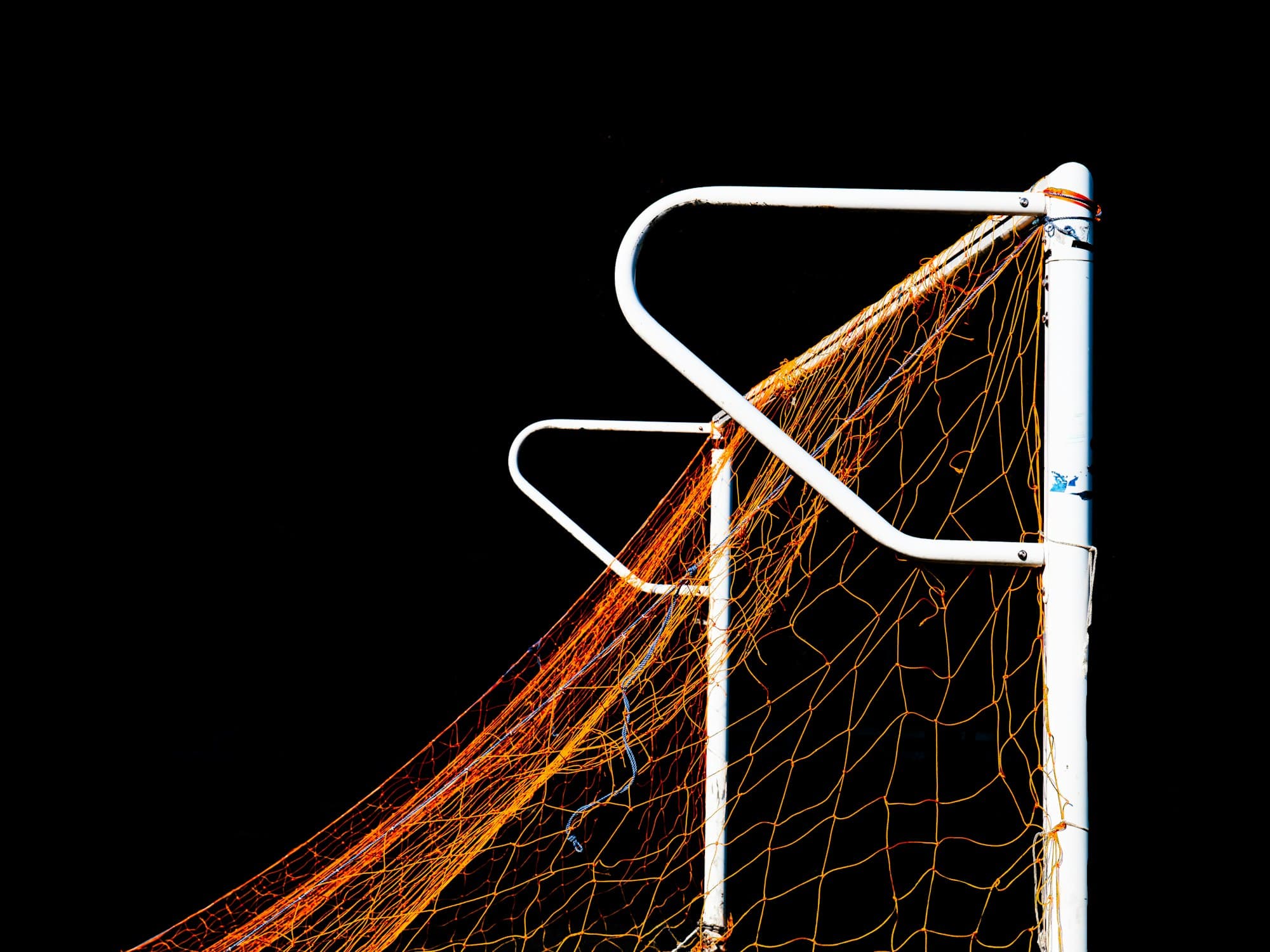 Close-up of football goal net against dark background