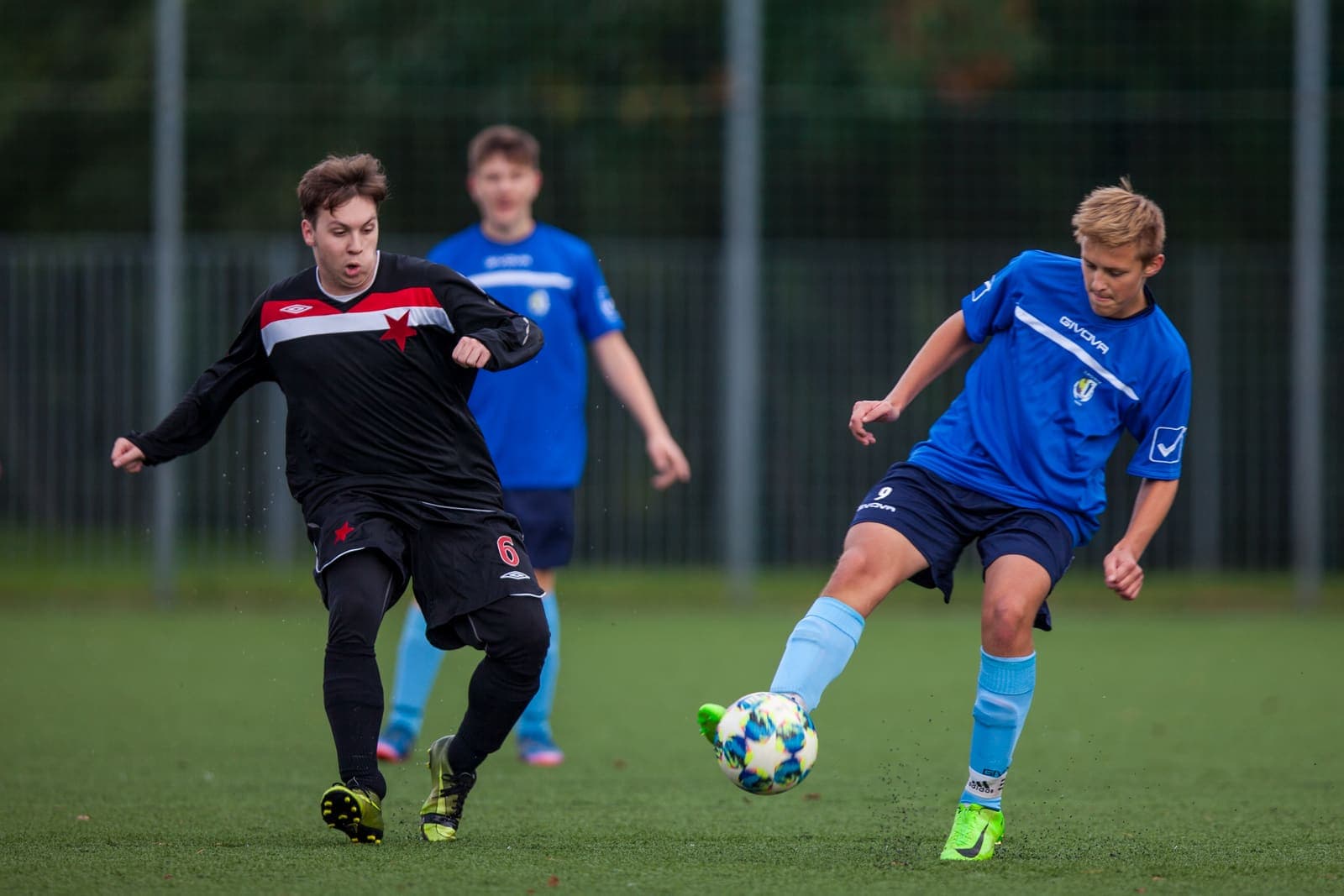 Youth footballer striking the ball as an opponent closes in
