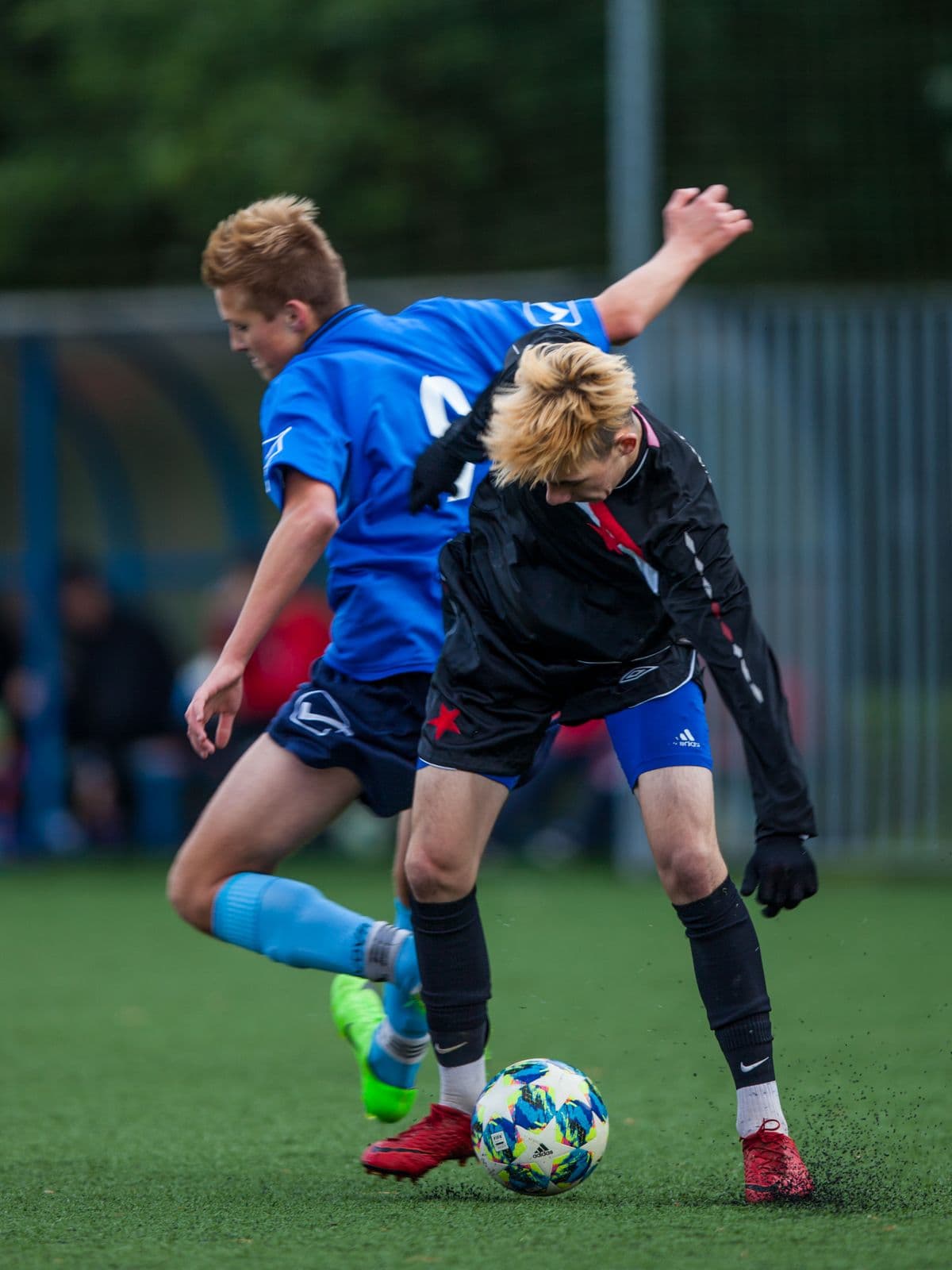 Youth footballers contesting the ball on an artificial pitch